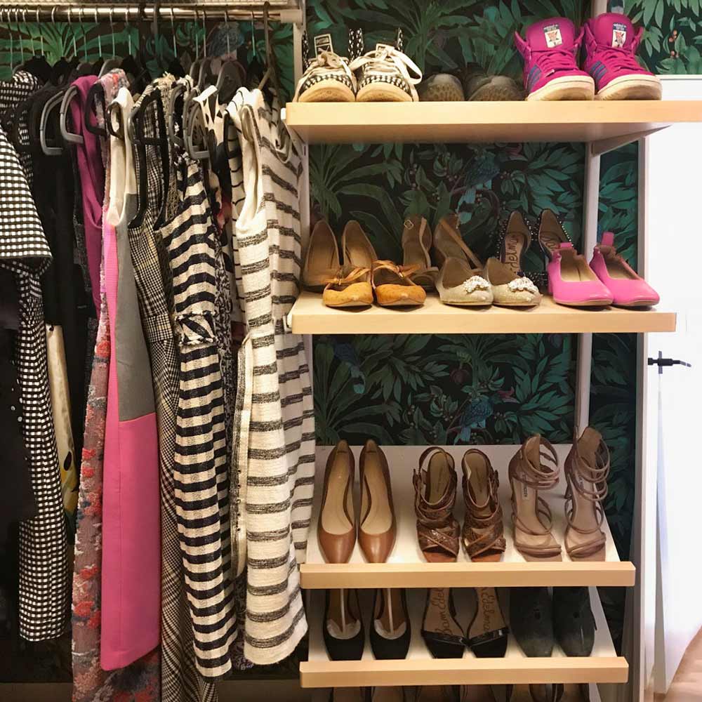 Closet organized by Caitlin Ruth with clothes arranged by color next to closet shelves with neatly aligned shoes.